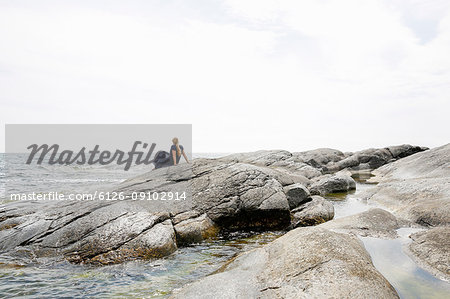 Mature woman sitting on rocky seashore in the Stockholm archipelago