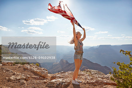 Young woman holding US flag at Grand Canyon