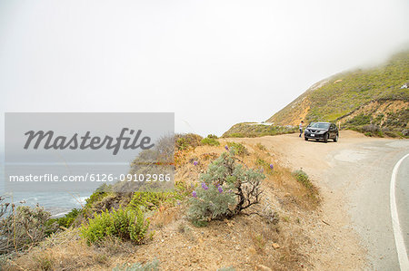 Boy and car by road overlooking sea at Big Sur