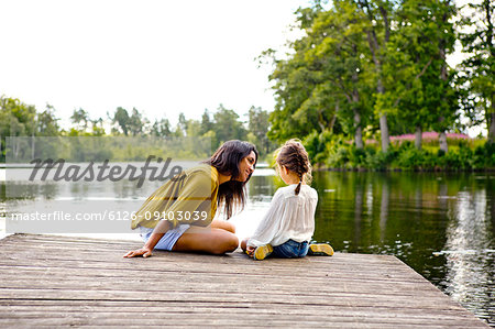 Mother and daughter on pier beside lake in Friseboda, Sweden