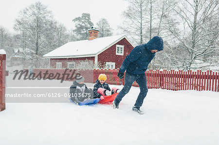Man pulling children on sled