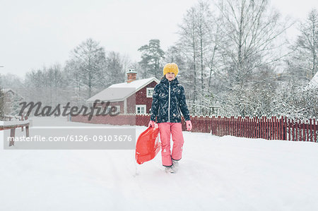 Girl holding a sled on snow