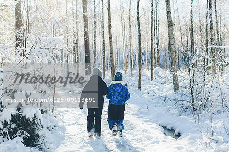Boys walking in forest during winter in Blekinge, Sweden