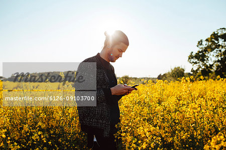 A young man outdoors looking at his cell phone