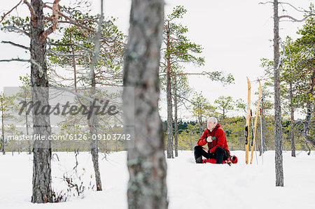 Mature man taking break from skiing in forest