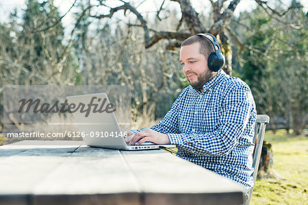 Mid adult man using laptop in garden