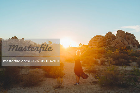 Woman wearing dress hiking in Joshua Tree National Park at sunset