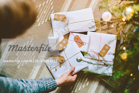 Man placing wrapped christmas gifts under tree