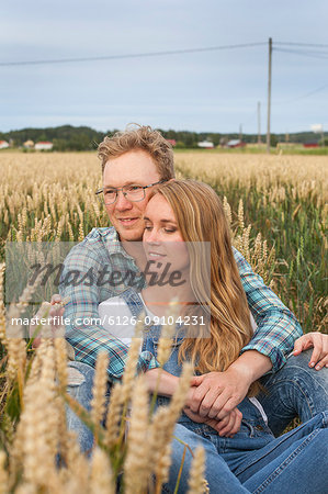 Mid adult couple sitting in wheat field