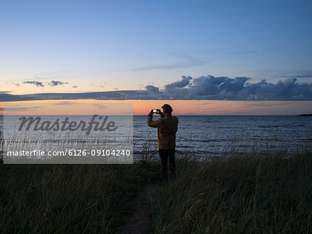 Man photographing moody sky over lake