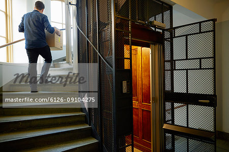 Man walking on steps, carrying box
