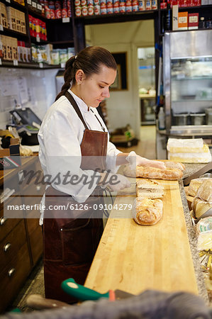 Woman cutting bread in store