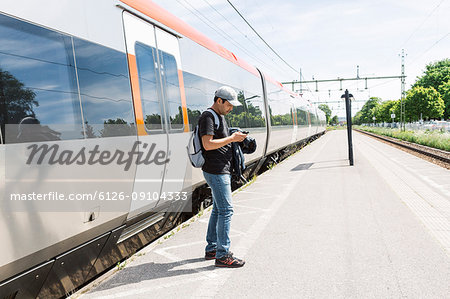 Man looking at smart phone on train platform