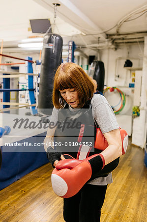 Senior woman putting on boxing gloves