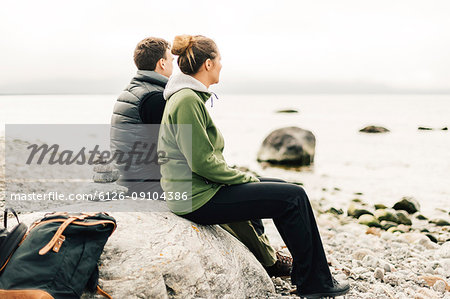Couple sitting on rock on coastline at Sodermanland, Sweden
