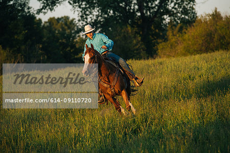 Teenage boy riding horse in field