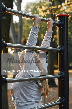 Curvaceous young woman training, gripping exercise bar in park