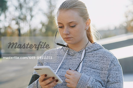 Young woman training, looking at smartphone