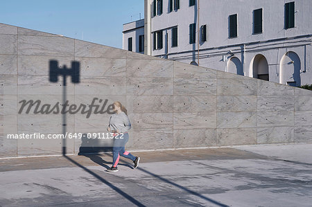Curvaceous young female runner running along sidewalk