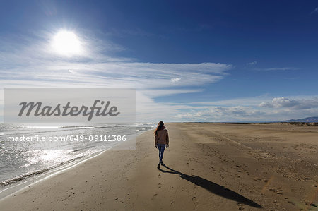 Rear view of young woman strolling along on beach, Tarragona, Catalonia, Spain