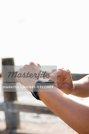 Young woman training on sea waterfront looking at smartwatch, close up of hands