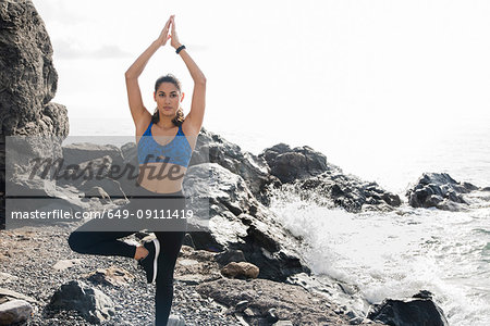 Young woman practicing yoga standing tree pose on beach, Las Palmas, Canary Islands, Spain