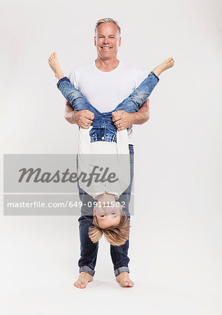 Portrait of father with son held upside down