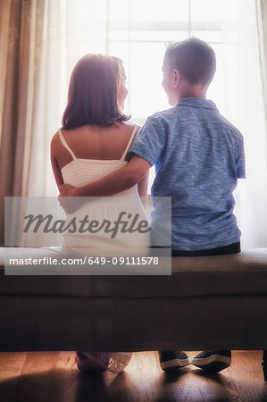 Boy and girl, sitting in front of window, rear view