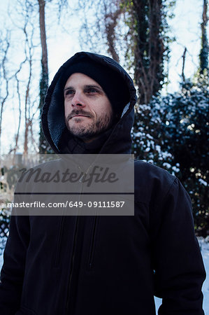 Man keeping warm in hooded jacket in winter weather