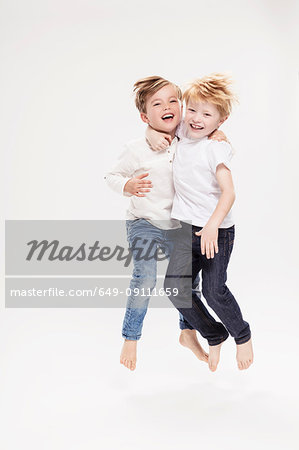 Studio portrait of two boys jumping mid air, full length