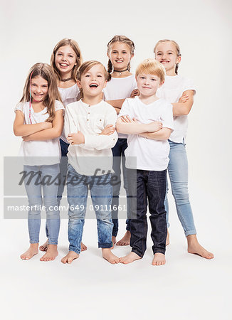 Studio portrait of two boys and four girls with arms folded, full length