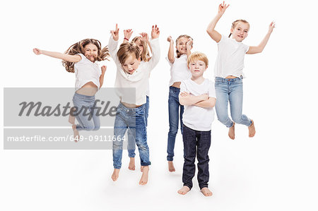 Studio portrait of two boys and four girls having fun jumping mid air, full length