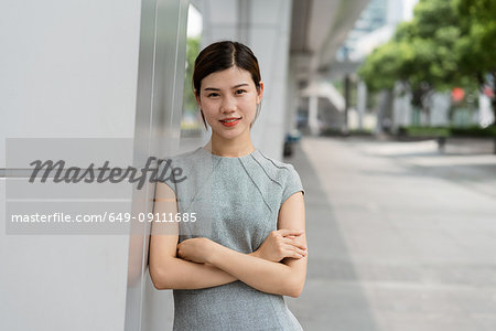 Portrait of young businesswoman leaning against wall in city, Shanghai, China