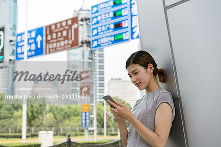 Young businesswoman looking at smartphone in city, Shanghai, China