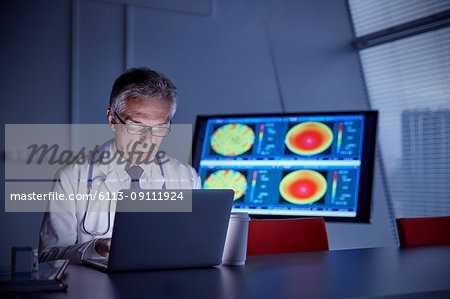 Focused male surgeon working at laptop in hospital