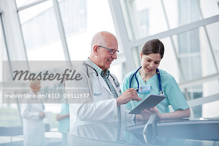 Doctor and nurse with digital tablet talking in hospital