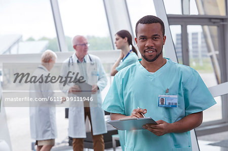 Portrait confident male nurse with clipboard in hospital lobby