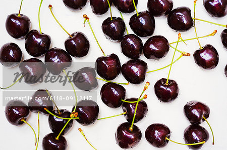 High angle close up of ripe red cherries spread out on a worktop.