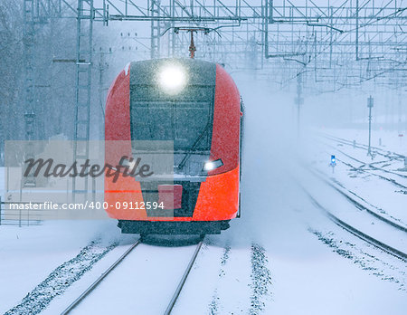 Highspeed train approaches to the station platform at snowstormy day time.
