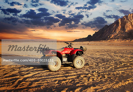 Quad bike in sand desert near mountain