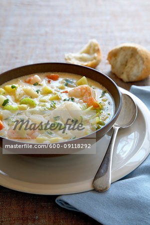 Bowl of seafood chowder soup with a spoon and crusty bread