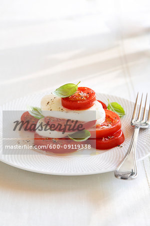 Caprese Salad on white plate with a fork