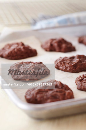 Freshly baked chocolate cookies on a cookie sheet with parchment paper
