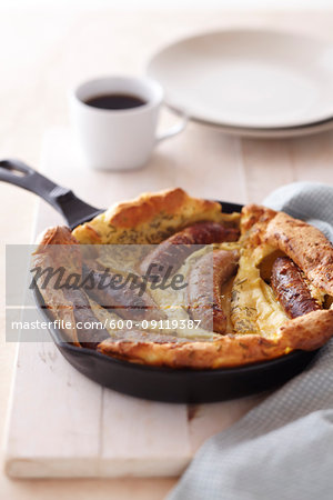 Baked sausage and pancake breakfast in cast iron skillet with a cup of coffee