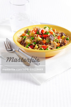 Fried Rice with pieces of beef, peppers, peas, celery, mushrooms and onion in a yellow bowl