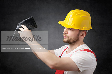 Construction worker looking for money in his empty wallet