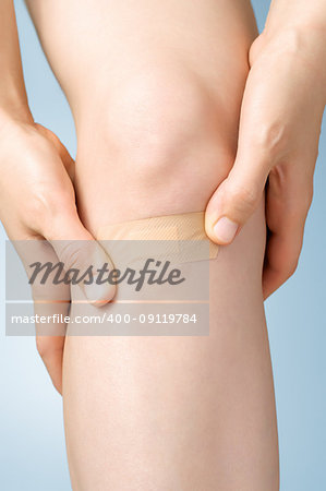 Woman putting an adhesive bandage on her leg