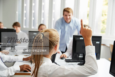 Teenage Students Asking Teacher Question In IT Class