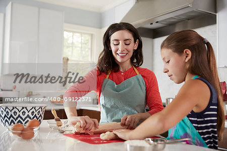 Jewish mother and daughter rolling dough for challah bread