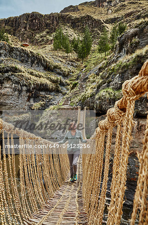 Mature woman crossing Inca rope bridge, Huinchiri, Cusco, Peru